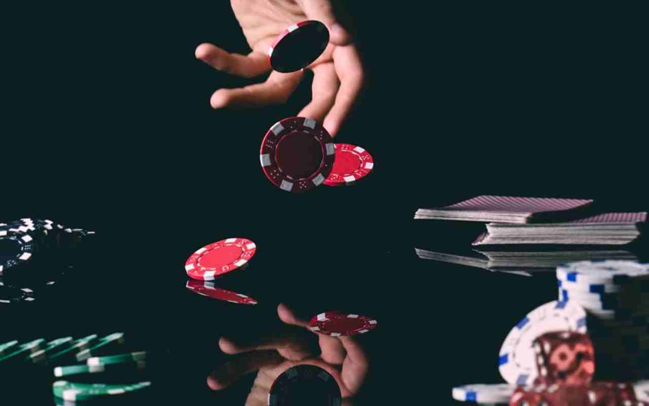 Osoba baca čipove za poker na sto pored karata