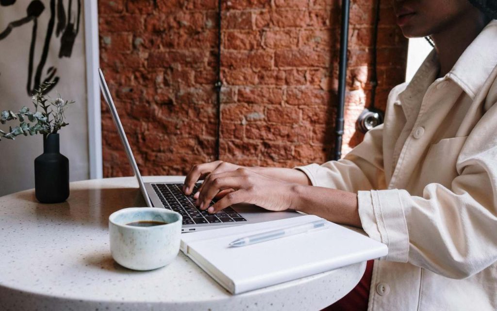 Žena sedi za stolom i kuca na laptopu