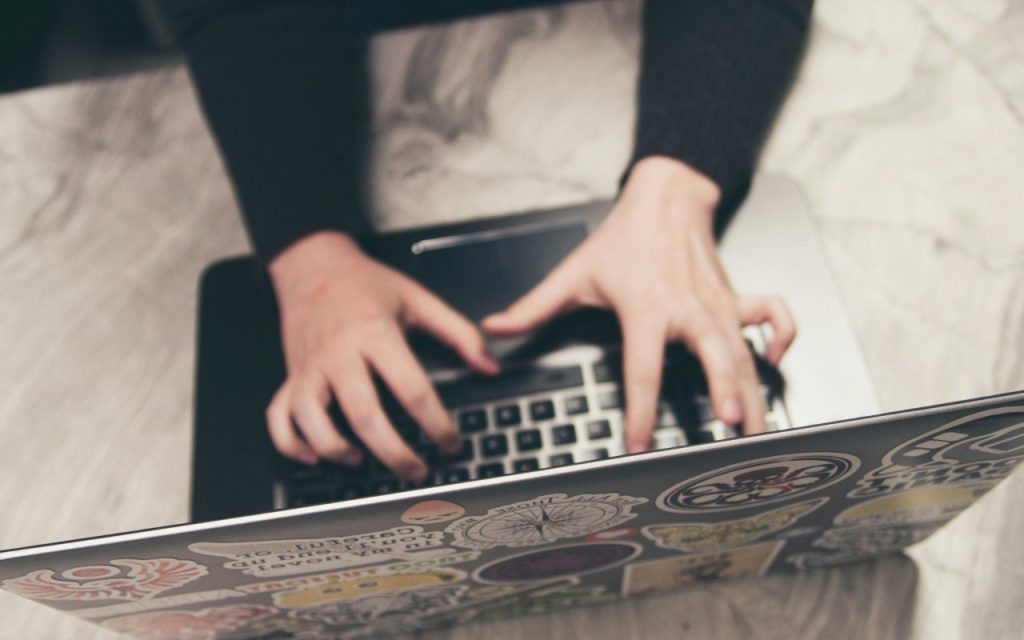 Osoba radi na laptopu koji ima stikere