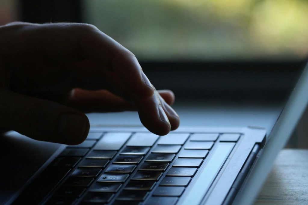 Ruka pritiska tastere na tastaturi prenosnog računara.